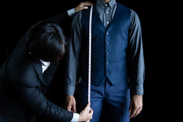 The dressmaker was using a tape measure to measure the length of the body on a black background.