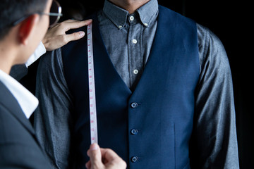 The dressmaker was using a tape measure to measure the length of the body on a black background.