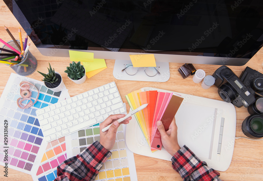 Wall mural Graphic designer artist creative looking at colour chart at desk in office.