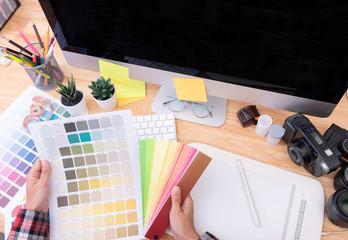Graphic designer artist creative looking at colour chart at desk in office.