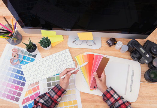 Graphic designer artist creative looking at colour chart at desk in office.