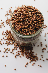 Raw buckwheat in glass on white background, heathy food, diet