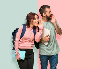Two students with backpacks and books shouting to the lateral and announcing something on colorful wall