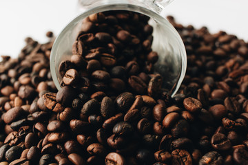 Close-up view of roasted coffee beans and glass cup