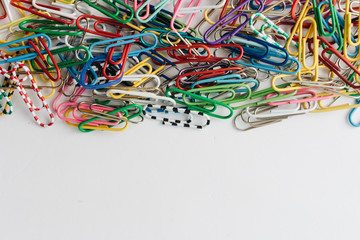 Pile of colorful paper clips on white background, flat lay