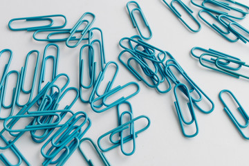 Pile of blue paper clips on blue background