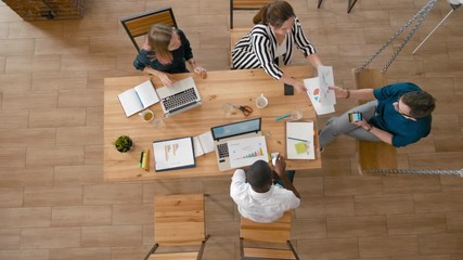 Overhead Team Leader Manager is Collecting Reports from Employees at Meeting in Startup Loft Office. Top View of Teamwork of Diverse Group of People. 4K High Angle Long Panning Gimbal Background Shot