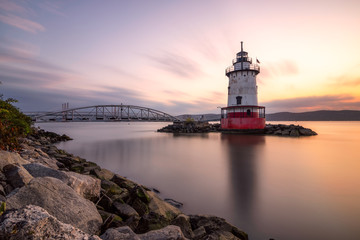 Caisson (sparkplug) style lighthouse under soft golden light with a bridge in the background. Tarrytown Light on the Hudson River in New York. 