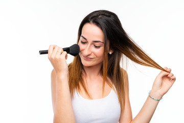 Young woman holding a lot of makeup brush over isolated white background