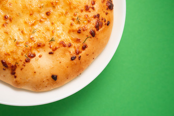 Fresh round cake on white plate on green background.