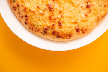 Fresh round cake on white plate on yellow background.