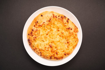 Fresh round cake on white plate on black background.