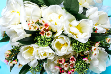 Beautiful bouquet of white tulips with green leaves and other decorative flowers close up, spring flowers.