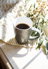 Cup of coffee, knitted sweater and autumn branches