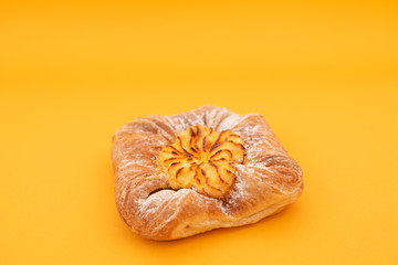 Fresh bun of unusual shape on yellow background.