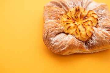 Fresh bun of unusual shape on yellow background.
