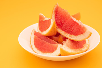 Fototapeta na wymiar Fresh ripe juicy grapefruit on white plate on yellow background.