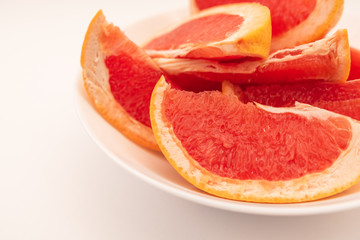 Obraz na płótnie Canvas Fresh ripe juicy grapefruit on white plate on white background.