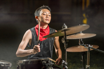 young boy as talented rock band drummer . portrait on stage of handsome and cool Asian American...