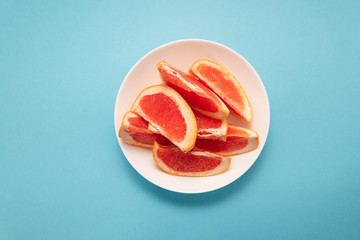 Fresh ripe juicy grapefruit on white plate on blue background.