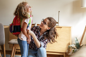 Mother preparing her daughter for first day in school.