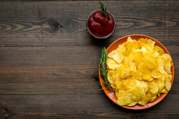 Homemade potato chips with ketchup for snack on wooden background top view copyspace