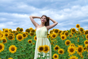 Fototapeta na wymiar Portrait of a young beautiful girl in a field of sunflowers