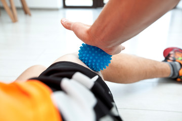 The man is massaging his leg by massage ball at home