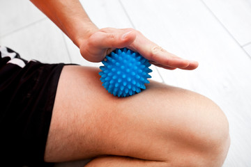 The man is massaging his leg by massage ball at home