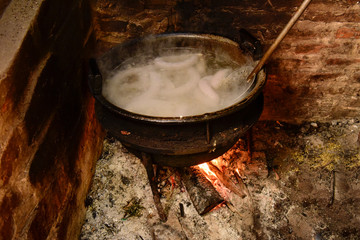 Cooking white blood sausage, in an iron saucepan, on a stove.