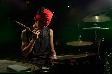 Fototapeta na wymiar Teenager rock band musician . 13 or 14 years old cool and talented Asian American mixed ethnicity young boy playing drums in headband practicing and performing song