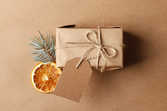 Decorative christmas  craft gift box with tag, Dried orange fruits,  fir branches, on craft background. Top view. Place for text