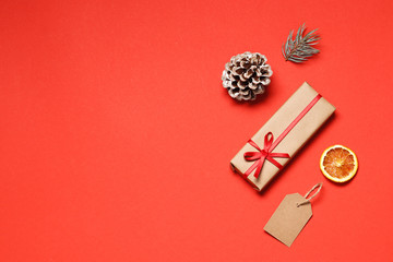 Flat lay composition of christmas gift box, tag, Dried orange fruits, fir branche, on a red background. place for text. Top view.