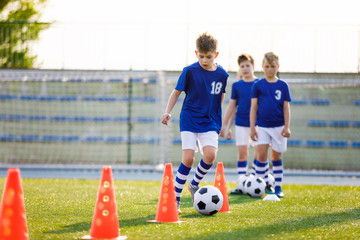 Football Training Dribbling Cone Drill. Young Boys of School Junior Soccer Team Practicing on Grass...