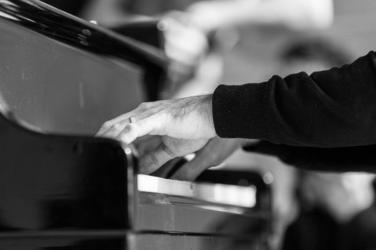 Monochrome image. Close up of man heands playing the piano.