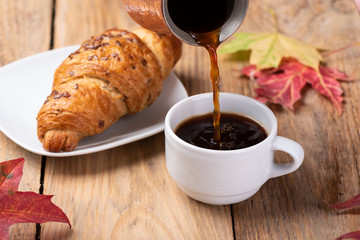 Pouring black coffee from a cezve into a cup.