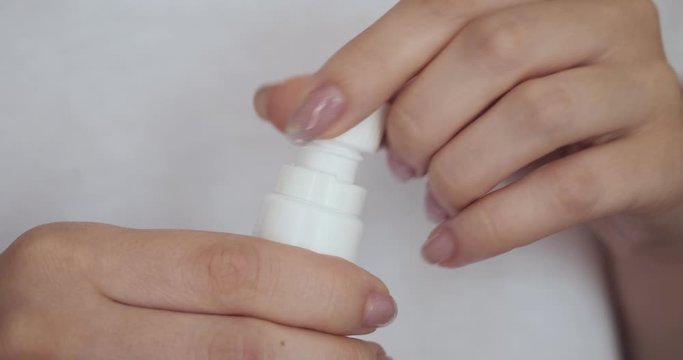 Female hands open white bottle.