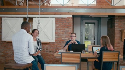 Positive Diverse Creative or Marketing Startup Team is Discussing Project in Loft Office with Flipchart, Laptops and Papers. Training or Seminar in Multiethnic Group of People. 4K Medium Long Shot