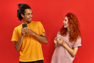 Optimistic joyful couple African American man and ginger woman in basic t-shirts looking at each...