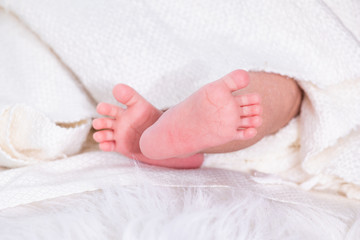 Selective focus 0-1 month newborn bare feet with tiny finger wrap by blanket or scarf