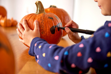 Close up of child drawing on halloween pumpkin