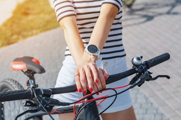 Fototapeta premium Woman's hand on bicycle handlebar, white smart watch on wrist