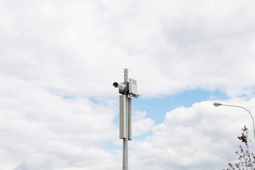 Security camera against the sky in the city. CCTV surveillance video equipment outdoor.