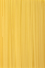 Thin pasta arranged in rows. Yellow italian pasta. Long spaghetti. Raw spaghetti wallpaper. Food background concept.