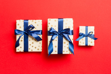 wrapped Christmas or other holiday handmade present in paper with blue ribbon on red background. Present box, decoration of gift on colored table, top view