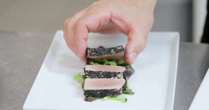 Chef sta tagliando tonno con sesamo nero su un tagliere di un ristorante