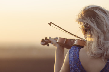 romantic young woman with a violin under her chin outdors, girl face relaxing in solitude with...