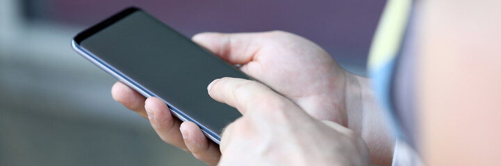 Focus on male hands holding modern smartphone. Man typing messaging on cellphone or using social media. Copy space on screen. Latest technology concept. Blurred background
