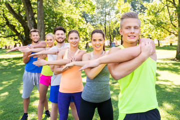 fitness, sport and healthy lifestyle concept - group of happy people exercising at summer park or...