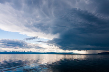 Storm with heavy rain and bright sun over the shore of lake Baikal